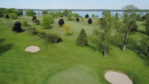 Flying over a golf course as a golfer putts a ball Stock Footage 158999987