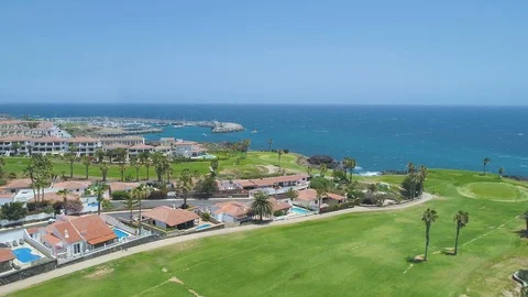 Flying over golf course green field towards blue ocean in sunny day Stock Footage 90553737