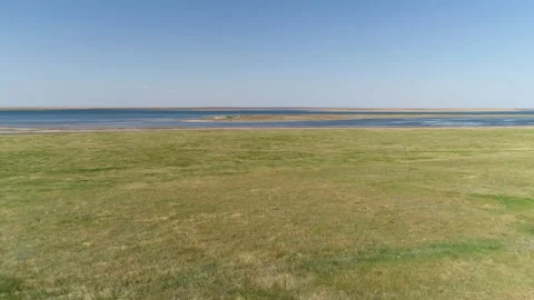 Flying over a green field, approaching the water Stock Footage 153481456