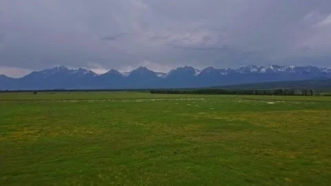 Flying over a green field on a drone without people near the mountains Stock Footage 159540423