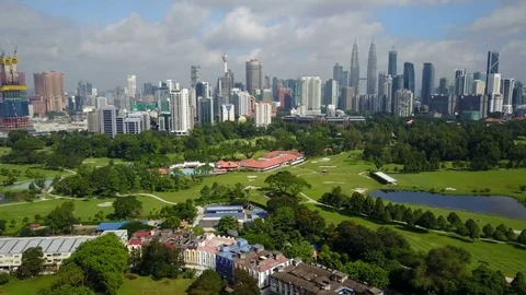 Flying over green golf course towards modern skyline Kuala Lumpur, Malaysia Stock Footage 78575313
