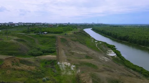 Flying over green meadows and a river in summer in cloudy Stock Footage 197853348