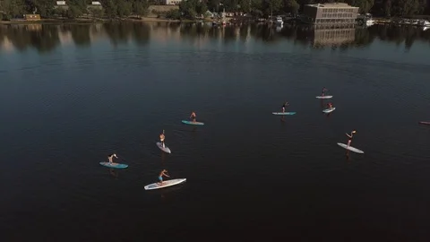 Flying over a group of people exercising on a sup board on a river against the Stock Footage 130110317