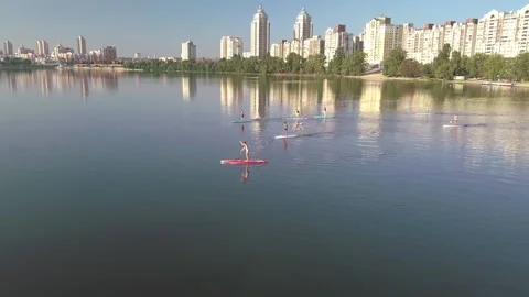 Flying over a group of people exercising on a sup board on a river against the Stock Footage 130323237