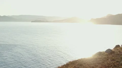 Flying over the hillside against the backdrop of the sea surface that sparkles w Stock Footage 151154584