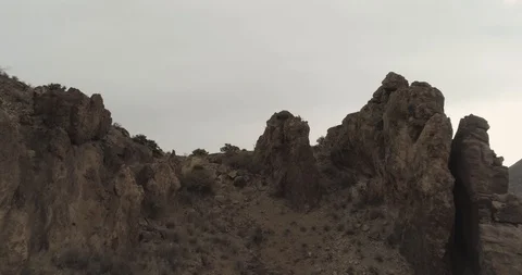 Flying over jagged rock faces rising up to reveal nearby town drone aerial 4K Stock Footage 111315975