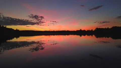 Flying over lake with reflection of sky and pink sunset Stock Footage 98085118