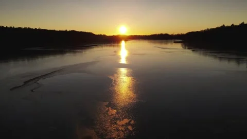 Flying over the lake in the setting sun. Ice on the water. Sunset, nature. Stock Footage 295133473
