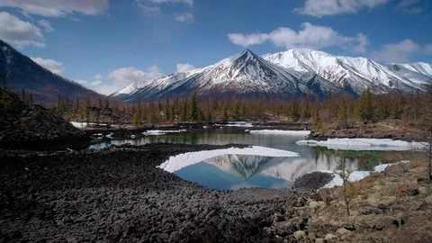 Flying over lakes with floating ice with snowcapped mountains around Stock Footage 99950311