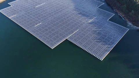 Flying over a large floating solar panel array on a reservoir in Sayreville Stock Footage 327371586