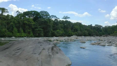 Flying over a large grey colored boulder that is lying in the riverbed Video stock 160314051