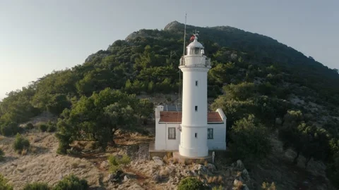 Flying over a lighthouse on the hill. Mountains on the background. Video stock 133077207