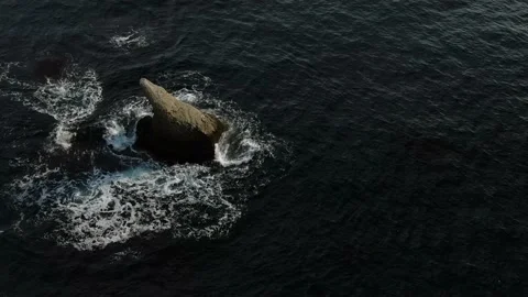 Flying over a lonely fin-shaped rock of a giant shark standing in the sea. Aeria Stock Footage 151140905