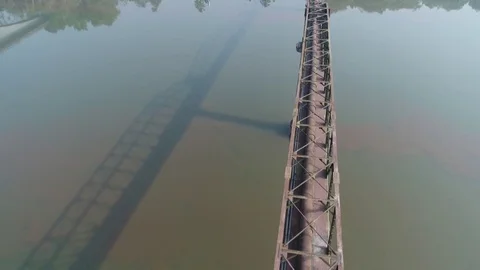 Flying over a long aqueduct over a muddy river. Aerial view. Stock-Footage 85452681