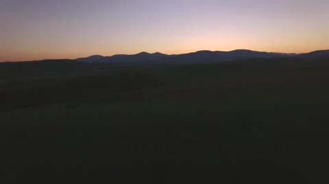 Flying Over Lush Green Rolling Hills at Dusk 库存影片 62492987
