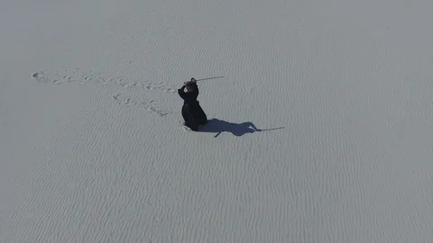 Flying over a man who is practicing martial arts in a desert Video stock 74578089