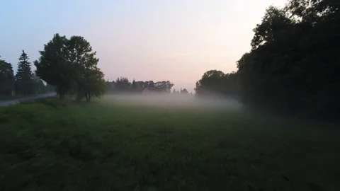 Flying over misty field towards house Stock Footage
