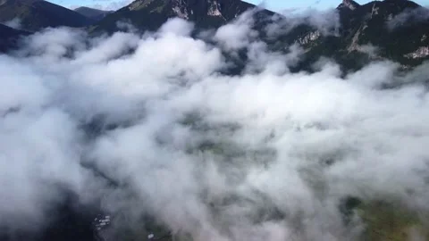 Flying over mountain alpine landscape, misty low clouds, fast movement Video stock 221788888