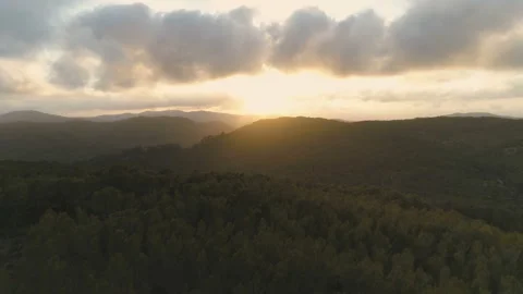 Flying over mountain forest towards beautiful clouds and golden hour sunset Stock Footage 108105307