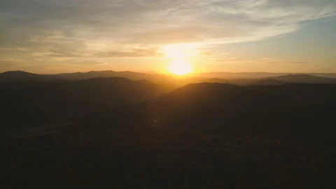 Flying over mountain forest towards clouds and golden hour sunset Stock Footage 108107389