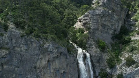 Flying over the mountains, pine forest to the waterfall Видео 156173921