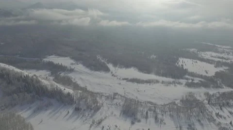 Flying over the mountains in winter on a background of clouds Stock Footage