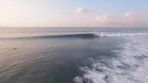 Flying over ocean with beautifully breaking waves and surfers at sunrise Vidéo 106547252