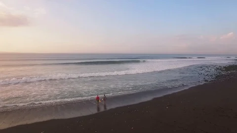 Flying over ocean with beautifully breaking waves and surfers at sunrise Stockbeeldmateriaal 106547264