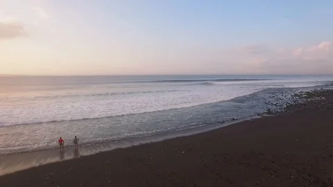 Flying over ocean with beautifully breaking waves and surfers at sunrise Vidéo 106547272
