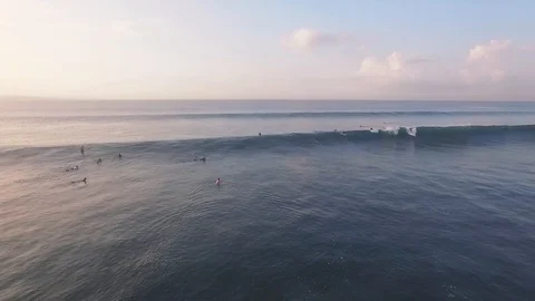 Flying over ocean with beautifully breaking waves and surfers at sunrise Vidéo 106547280