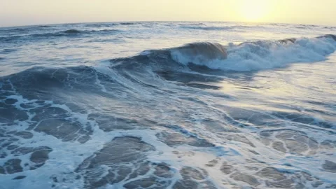 Flying over the ocean during golden hour. Giant waves foaming and splashing in Stock Footage 155454093