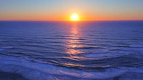Flying over ocean sunset with glowing orange purple and blue tones on waves Stock Footage 305492766