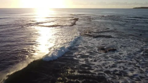 Flying over ocean surf waves breaking on rocks at sunrise Video stock 151877543