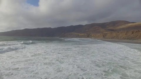 Flying over ocean waves along a beach and cliffside Stock Footage 90564058
