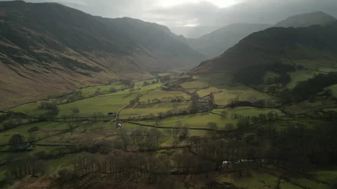 Flying over patchwork fields and reveal of hidden valley with misty Stock Footage 233950877