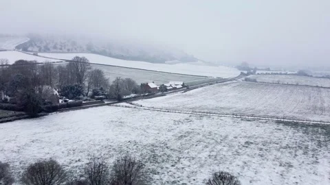 Flying over a patchwork of snowy fields in winter towards a salted road Stock Footage 225460635