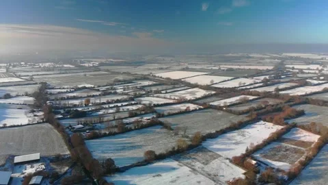Flying over a patchwork of snowy fields in winter sunshine. Beautiful blue sky Video stock 226394611