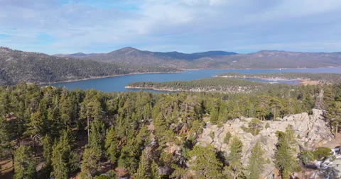 Flying over pine forest revealing lake and mountains Stock Footage 329901644