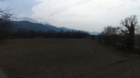 Flying over ploughed fields with mountains in background Stock Footage 99116995