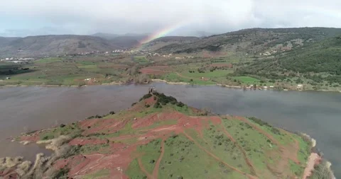 Flying over a red mountain along lake Salagou reveals the rainbow in the back Stock Footage 196300850