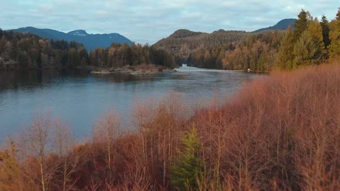 Flying over red trees towards a pristine mountain lake and river at sunset. Stock Footage 104451309