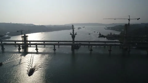 Flying over river along construction of a huge bridge. Aerial view. Stock-Footage 85530994