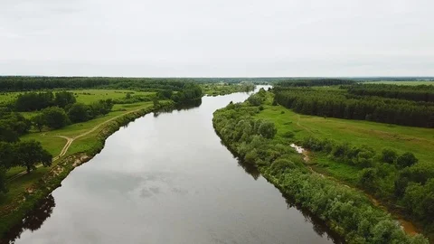 Flying over the river flowing along the fields and forests Stock Footage 92992199