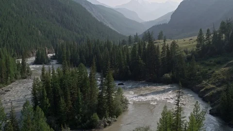 Flying over a river flowing through a forest a gorge. To the snowy mountains 4K Stock Footage 124743711