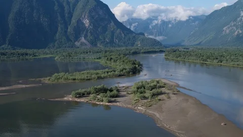 Flying over a river that flows into a lake against the backdrop of mountains 4k Stock Footage 125325262