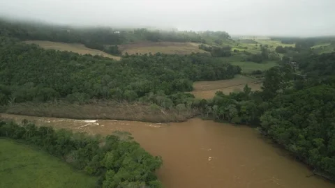 Flying over a river, forest and green fields. Low clouds. Aerial. Video stock 233218332