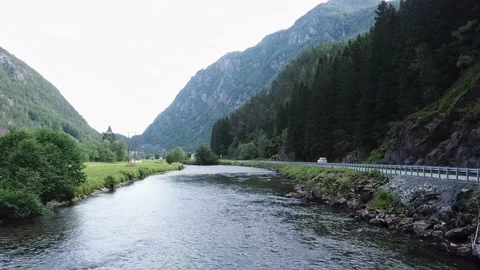 Flying over the river next to the road in the gorge, mountains in the background Stock Footage 224138843