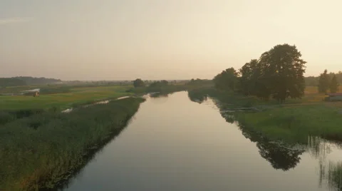 Flying over River Surrounded by Large Green Forest at Sunset Time Stock Footage 68399924