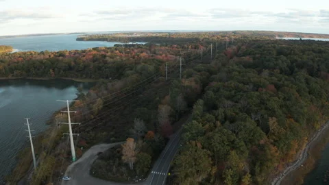 Flying over road parallel to power lines on island of dense woodland Video stock 143281839