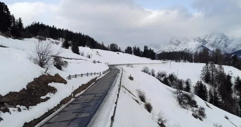 Flying over a road in a snow covered mountain in Switzerland. Stockbeeldmateriaal 92943574